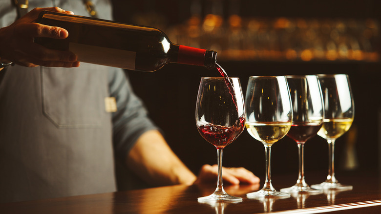 Four glasses of wine being poured