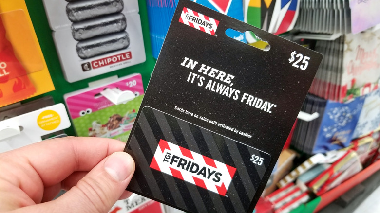 Hand holding a TGI Fridays gift card in a store
