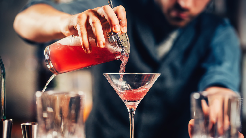 Person pouring a cosmopolitan into a glass