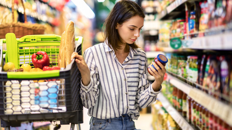 Woman picking up jar in grocery store