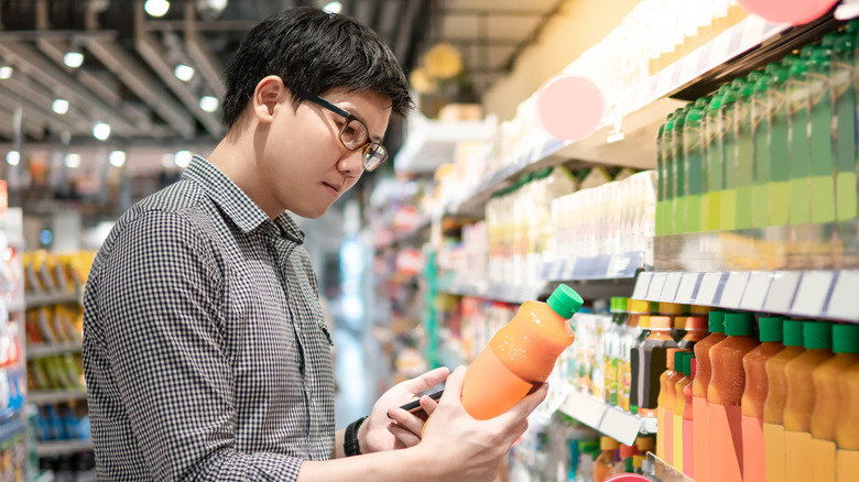 Man looking at carrot juice in grocery store