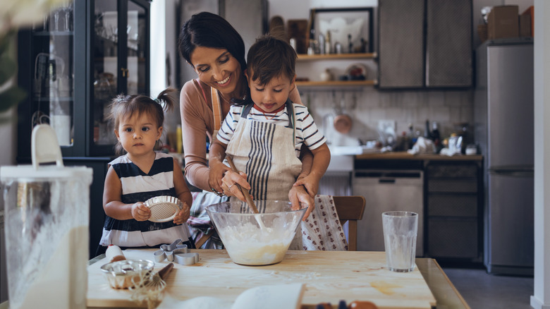 Woman mixing cake batter with children 