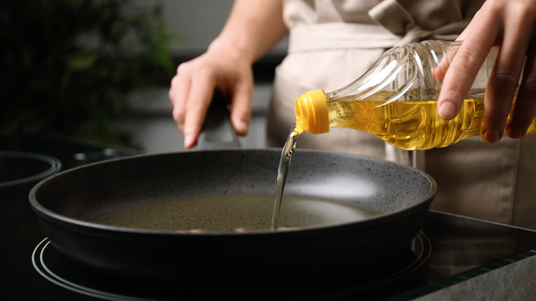 cook pouring oil into pan