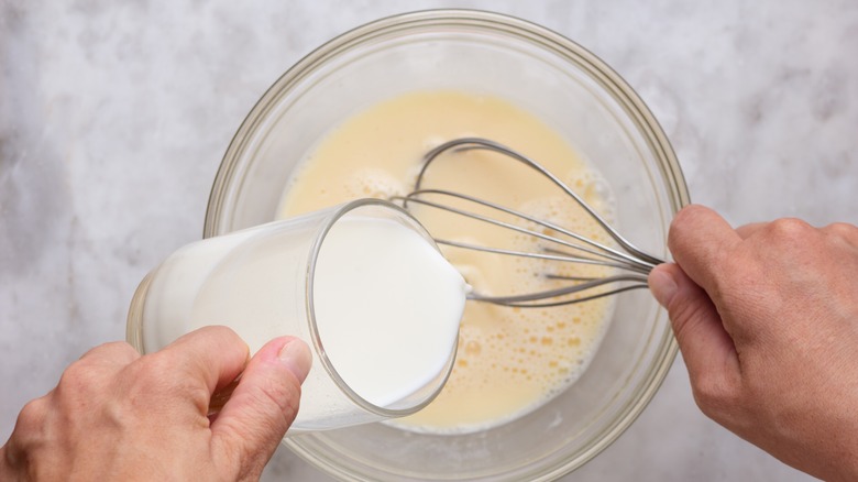 Cook mixes pancake batter in bowl with whisk