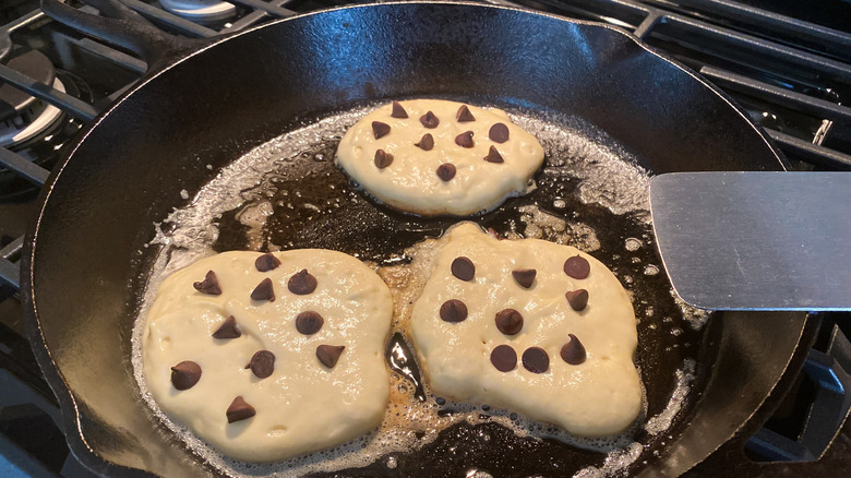 Raw pancake batter on cast iron skillet with chocolate chips on top.