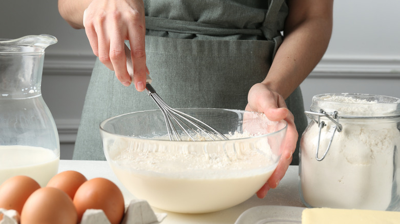 Close-up of person whisking batter in glass bowl.
