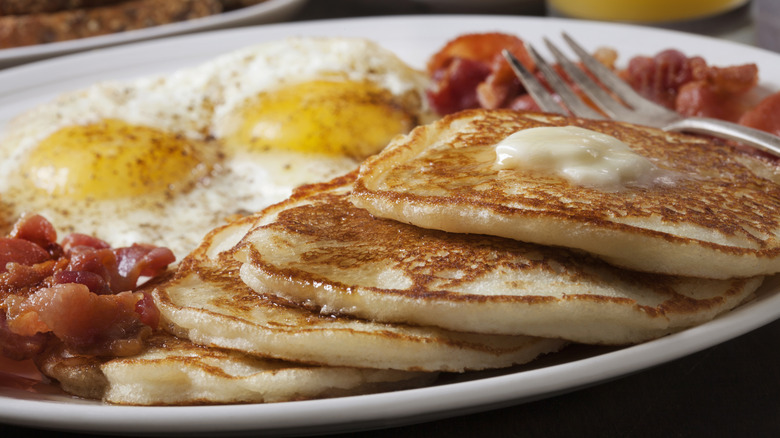 Diner-style pancake breakfast with eggs and bacon.