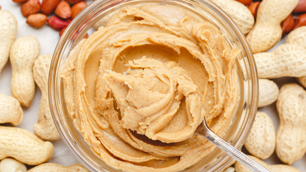 Peanuts surrounding jar of peanut butter