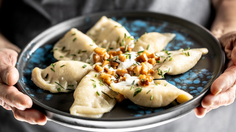 Person handing a plate of pierogis