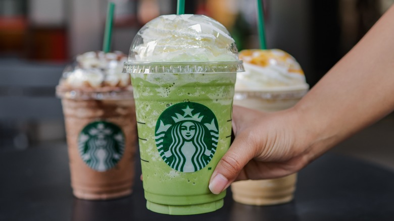 three frappuccinos being handed off