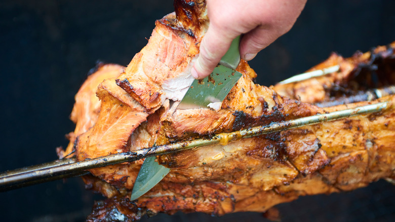 Slicing meat off barbecue hog