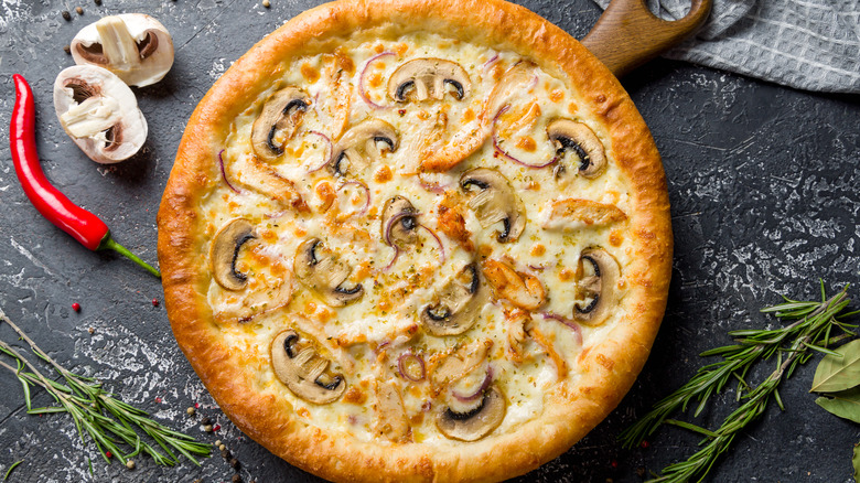 Mushroom pizza with a pepper next  to it