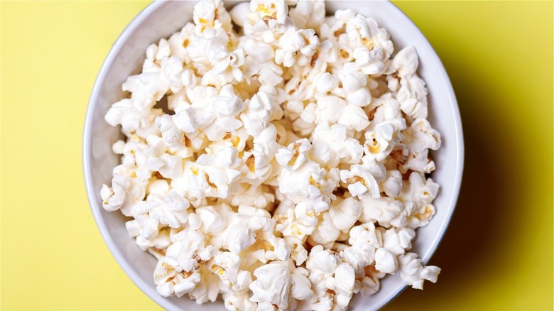 Popcorn in a while bowl on yellow background