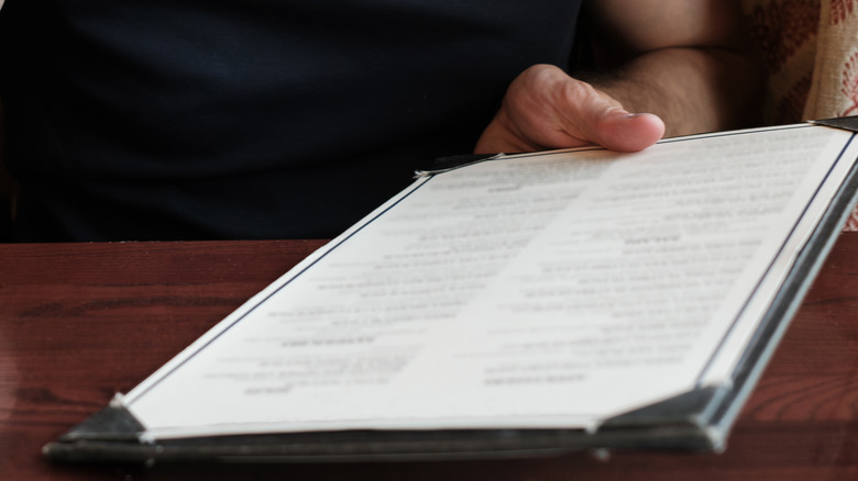 Man in dark shirt holding a restaurant menu