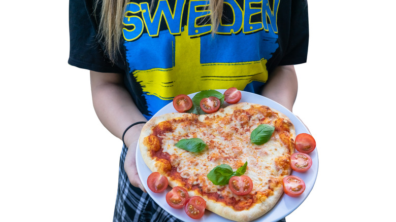 person holding heart-shaped pizza