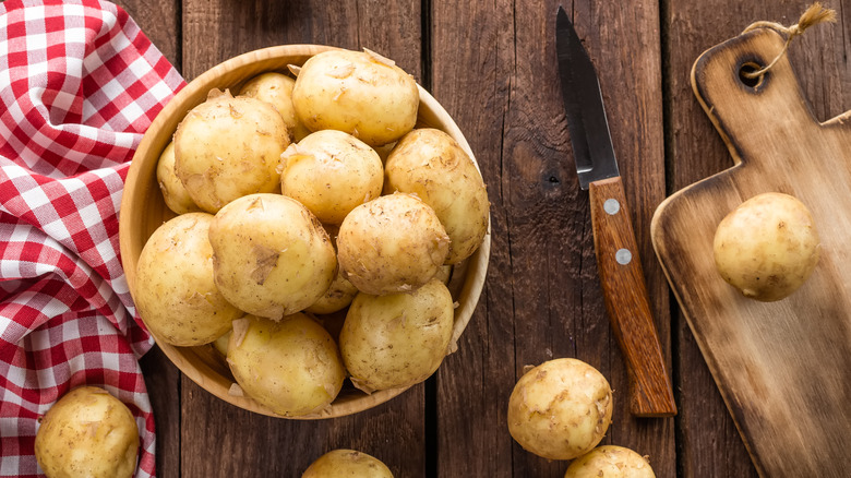 Bowl of potatoes with knife and cutting board