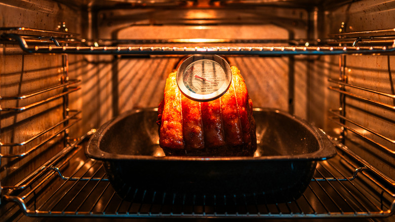 Rib roast in roasting pan in the oven with food thermometer.