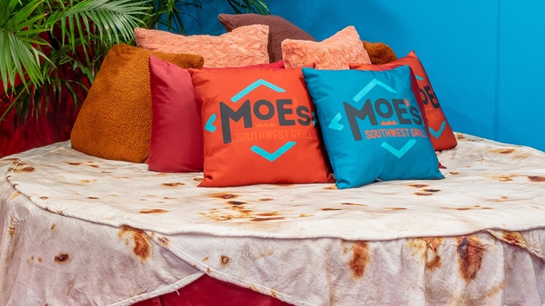 bed at Moe's Airbnb with blanket shaped tortilla and colorful Moe's pillows