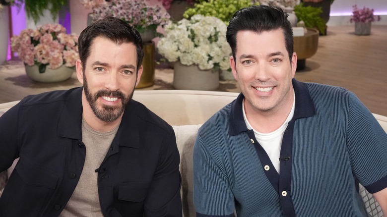 Drew and Jonathan Scott seated on a couch, smiling