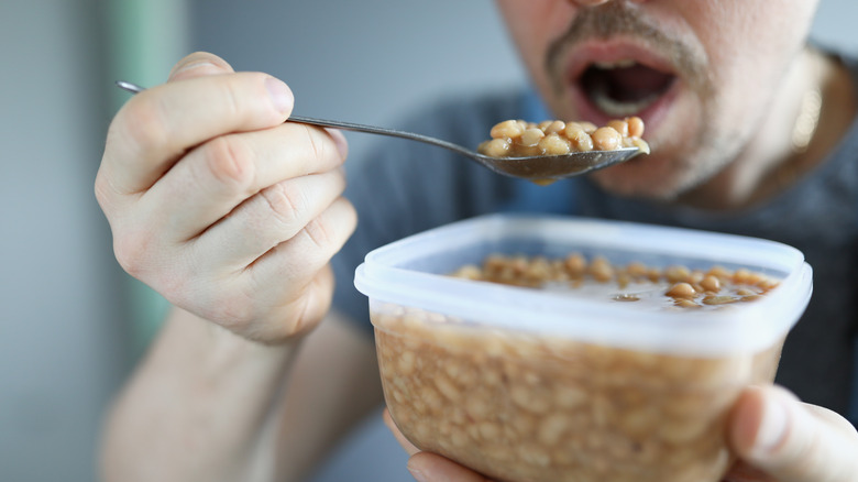 man eating beans from tupperware