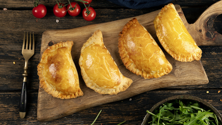 cooked empanadas on cutting board