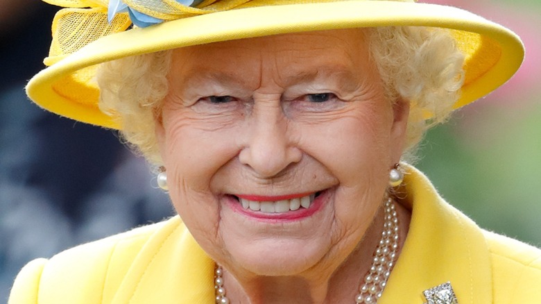 queen elizabeth II with wide smile and yellow hat