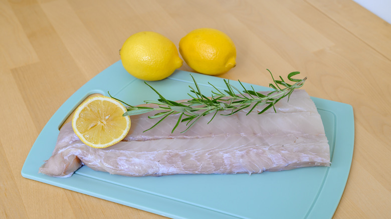 Cod fillet on cutting board with lemons