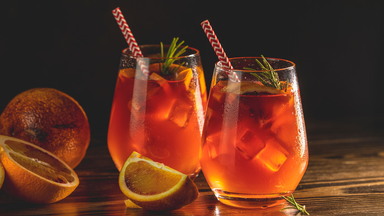 Two orange cocktails with fruit