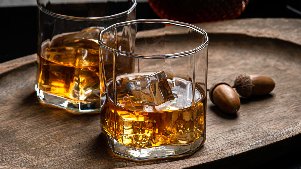 two glasses of bourbon with wood background