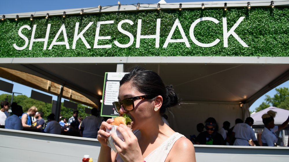 A woman eats a Shake Shack burger
