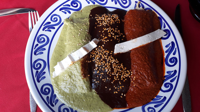 Green, black, and red mole varieties on a plate