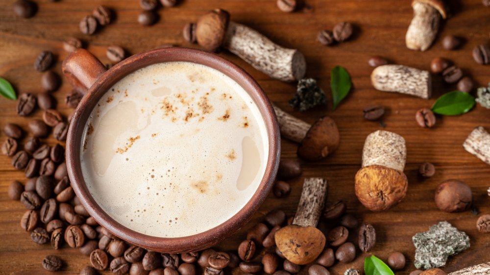 Cup of mushroom coffee surrounded by mushrooms and coffee beans