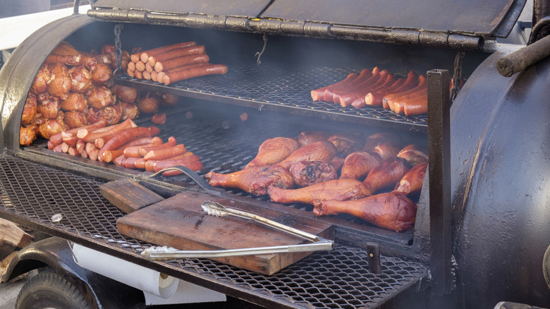 Metal smoker grill with various meats cooking