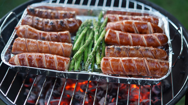 Sausages in aluminum tray on grill