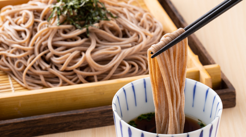 Soba noodles being dunked into broth