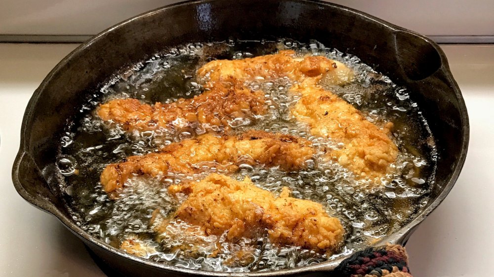 Frying chicken in oil in cast iron pan
