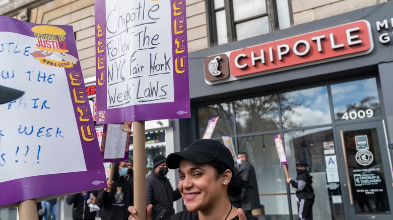 Protestor holding sign outside a Chipotle