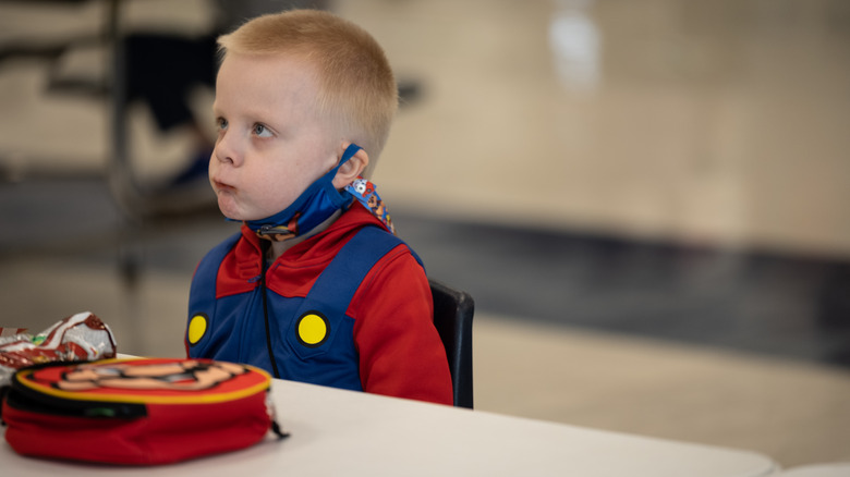 schoolchild frowning with no lunch in front of him