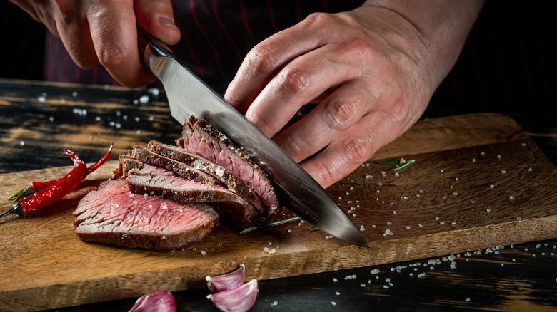Hands slicing a steak