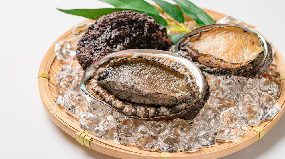 Abalone in its shell on a wooden platter