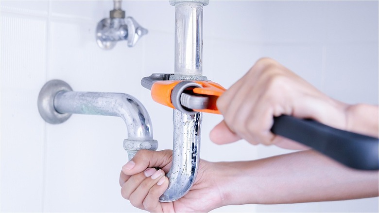 person using wrench to fix pipe