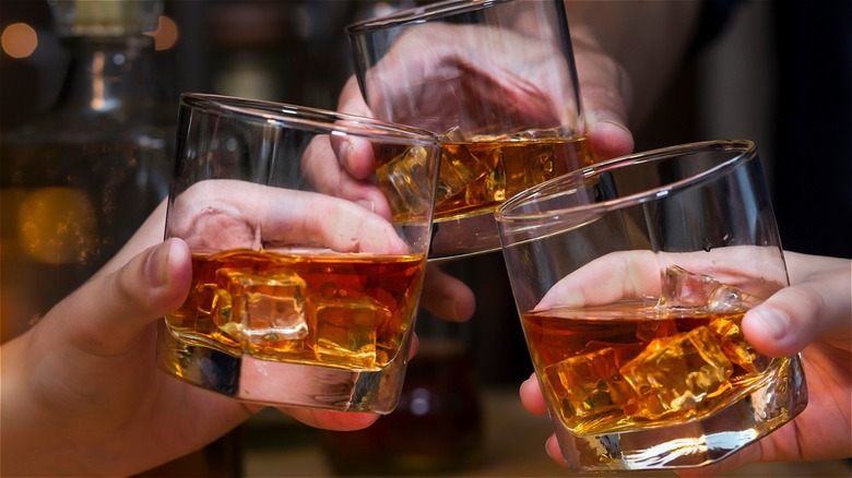 Bourbon glass, ice, toasting friends