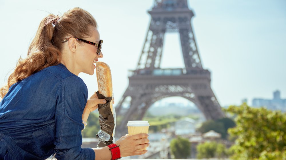 Woman eating a baguette in front of the Eiffel Tower