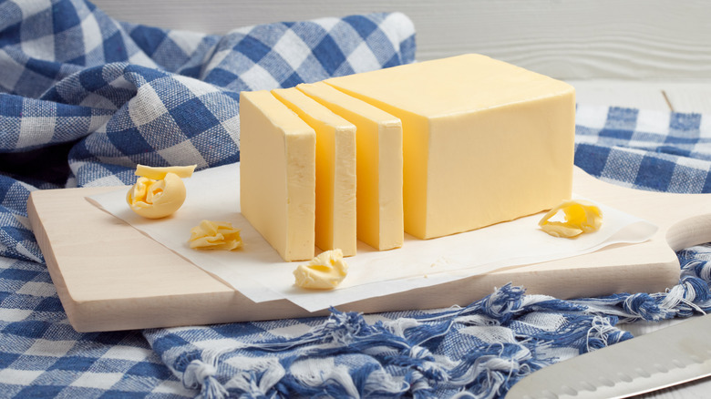 Stick of butter cut into chunks on wooden board