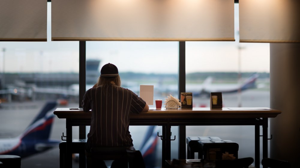 Person eating at an airport in front of window with planes outside