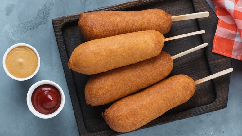 Corn dog on tray with dipping sauces