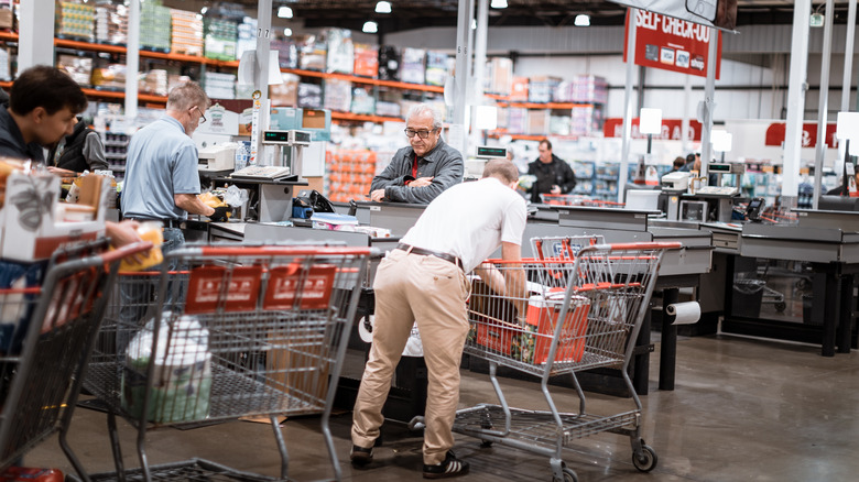Customers and cashiers in checkout lanes at Costco