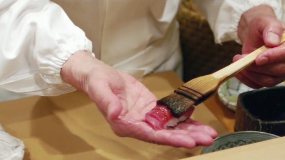 Preparing a slice of tuna sushi for serving