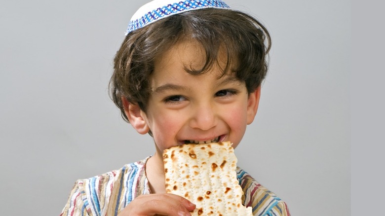 A little boy munching on matzo