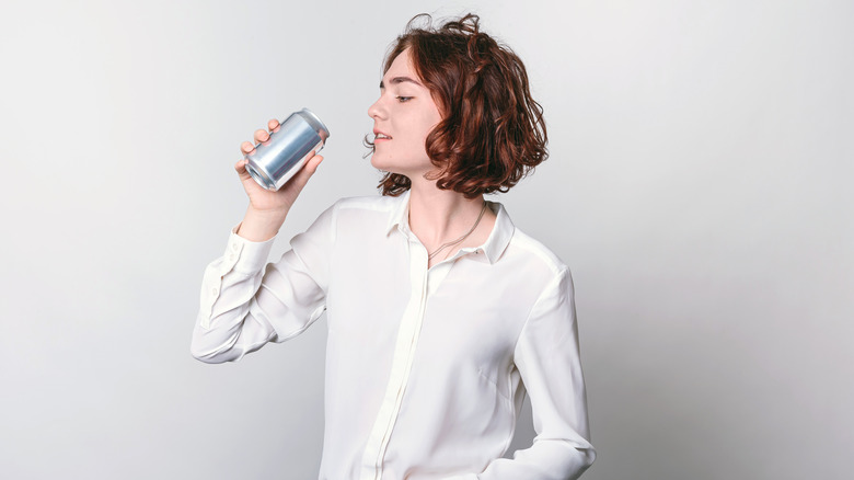 woman drinking out of soda can